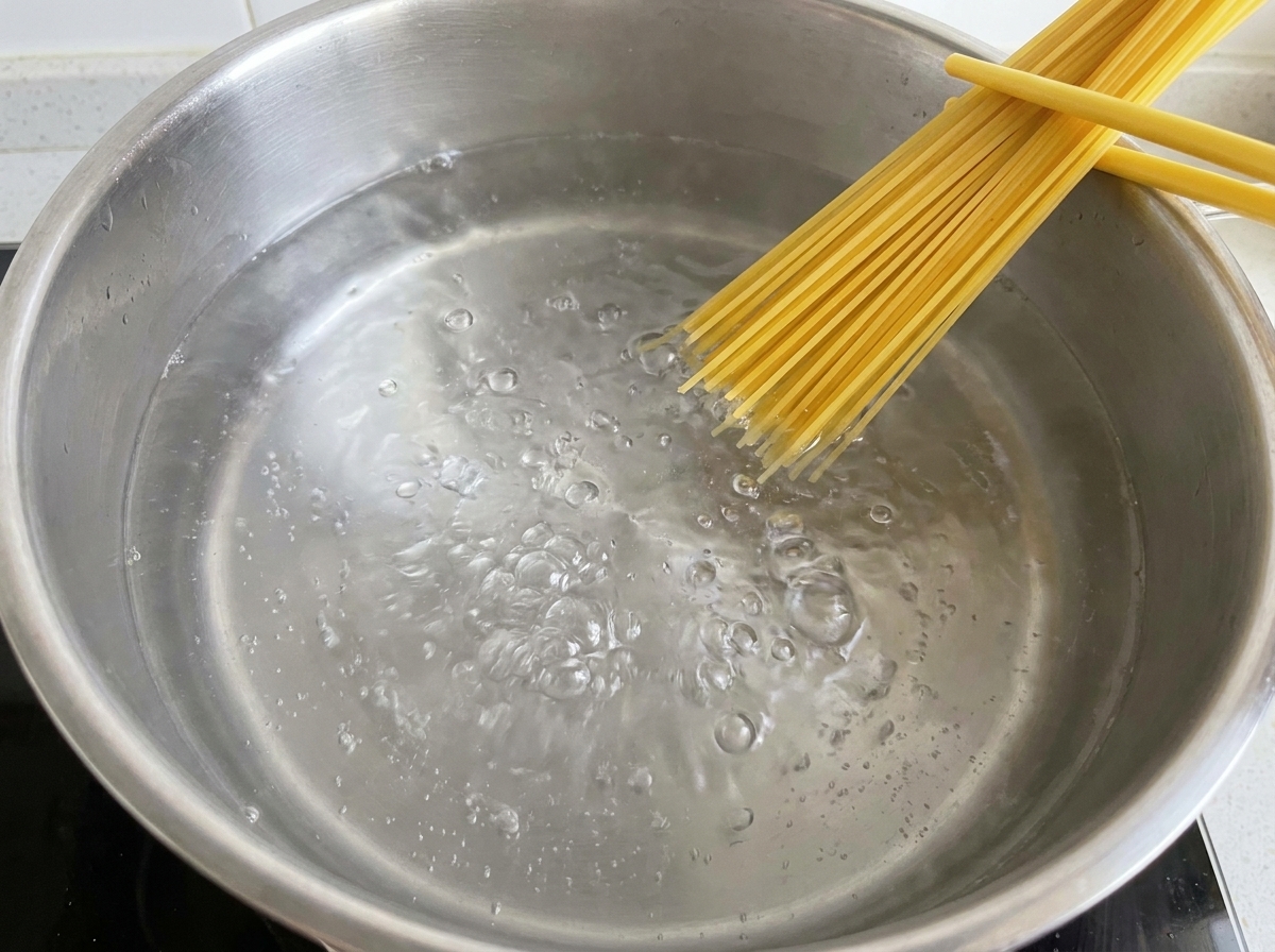 Spaghetti secs plongés dans une casserole deau bouillante salée.