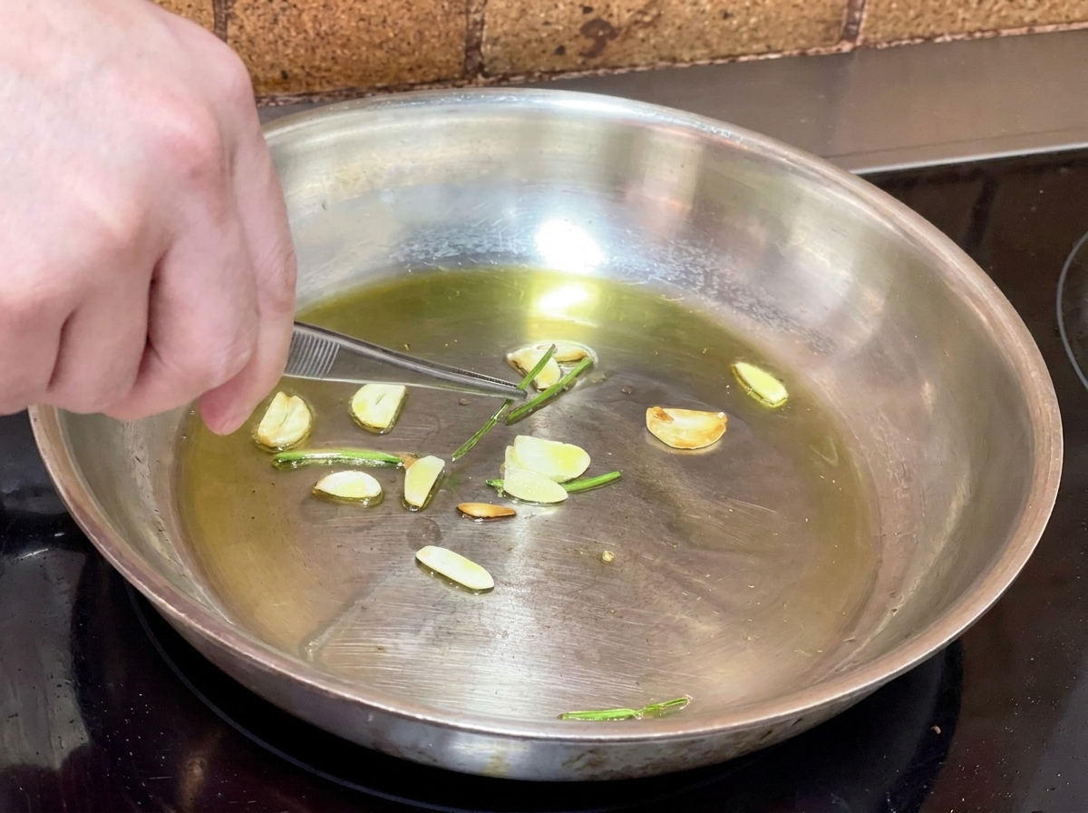 Pince de cuisine retirant les tiges de persil frit dune poêle dhuile infusée.