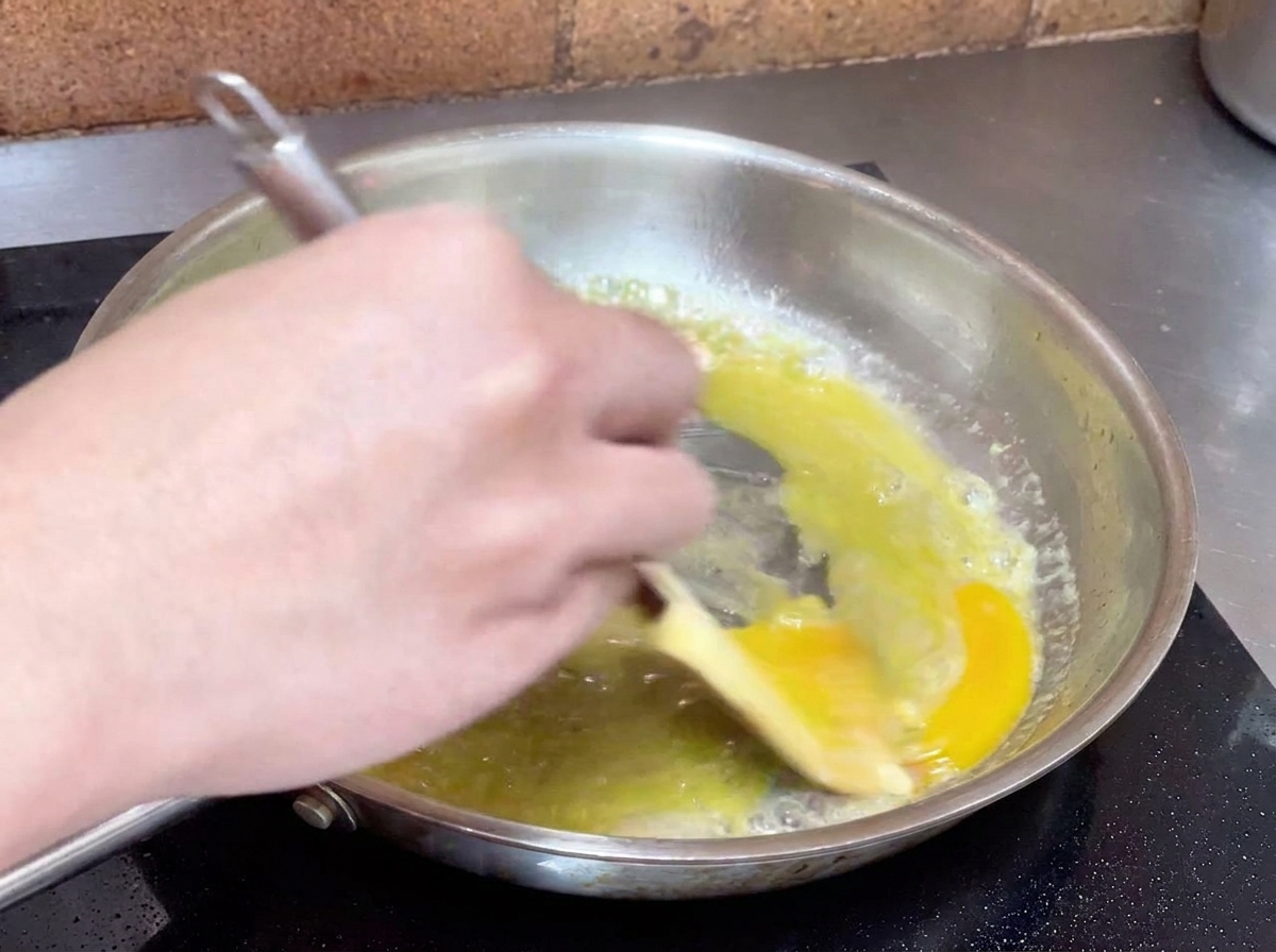 Main remuant énergiquement le mélange dhuile et deau avec une spatule pour créer une émulsion crémeuse.