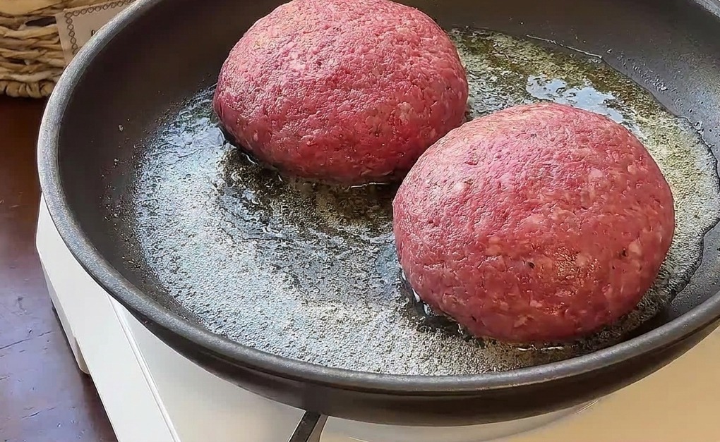 Deux steaks de bœuf épais en train de griller avec du beurre dans une poêle sur un réchaud.