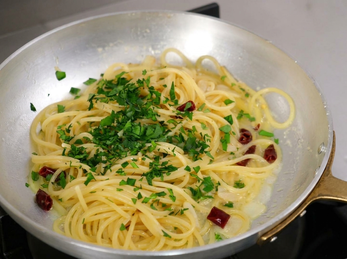 Persil frais haché saupoudré généreusement sur les spaghetti cuits dans la poêle.