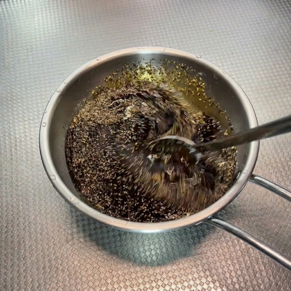 Mélange rapide dune sauce sombre au poivre noir avec une cuillère dans un bol en métal.