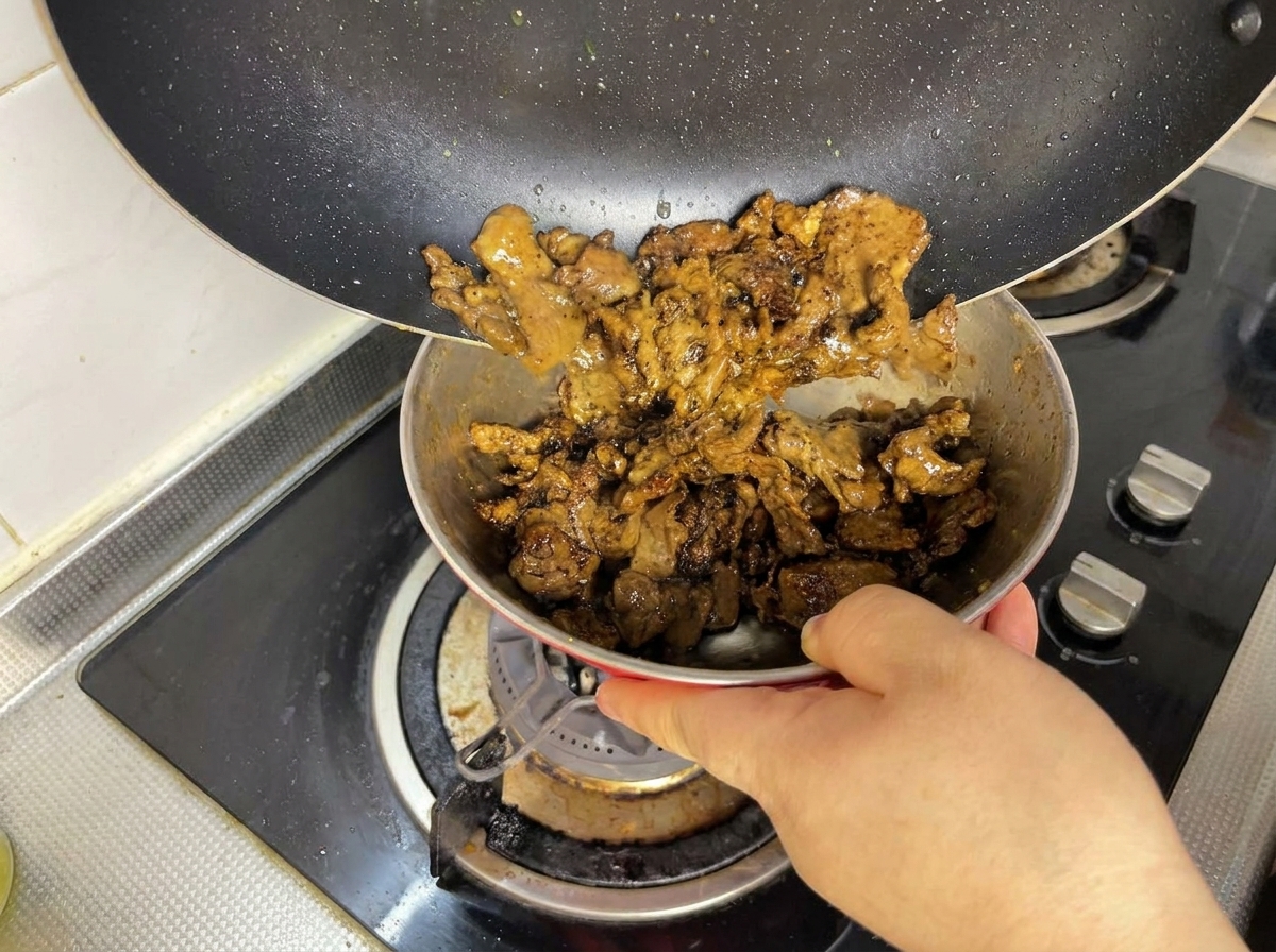 Morceaux de bœuf dorés versés dune poêle noire dans un petit bol en métal.
