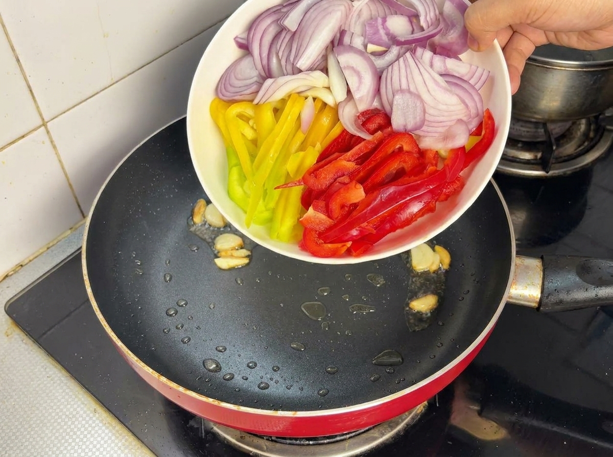 Oignons rouges et poivrons colorés ajoutés dune assiette dans une poêle chaude avec de lhuile.