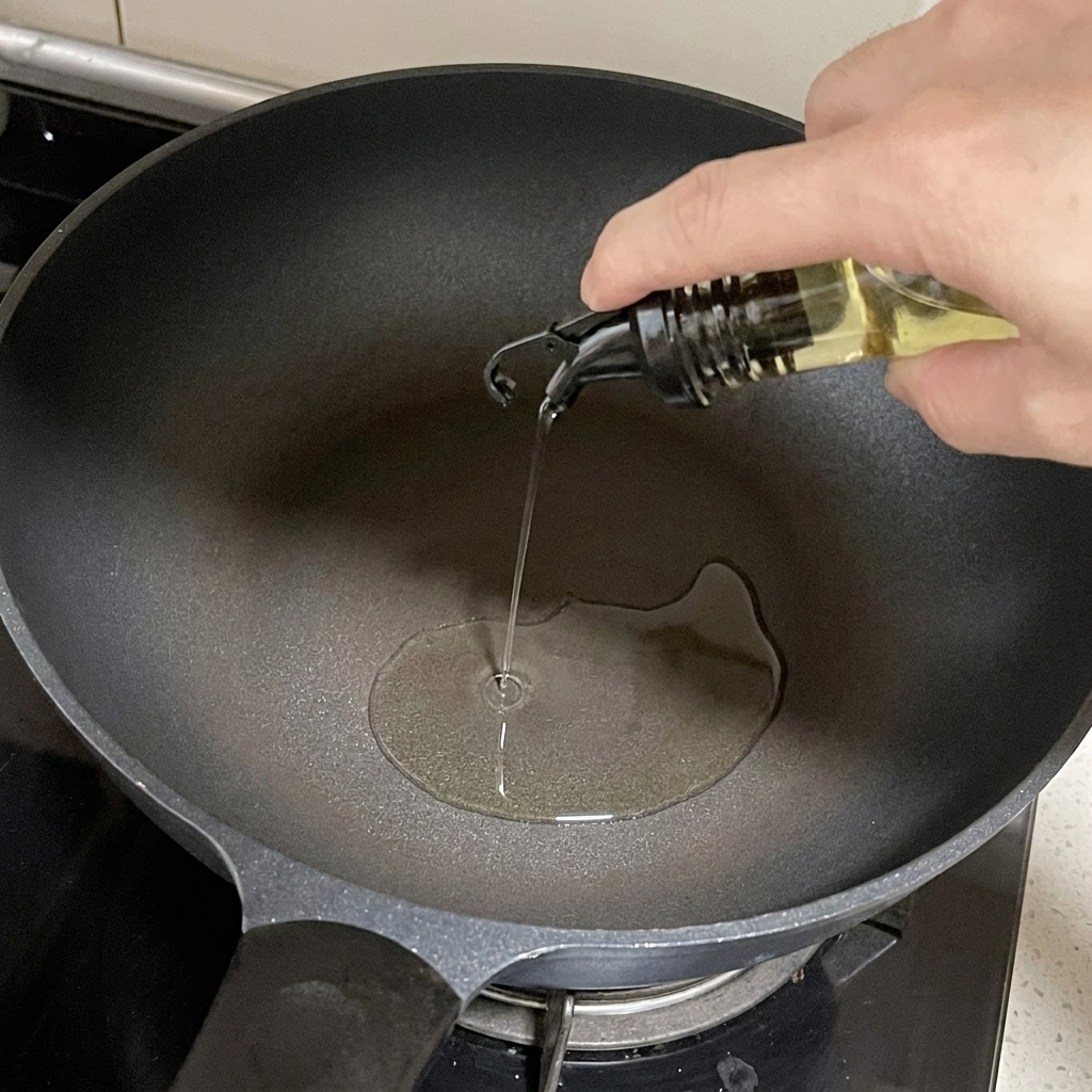 De lhuile de cuisson versée depuis un distributeur en verre dans une poêle sombre sur la cuisinière.