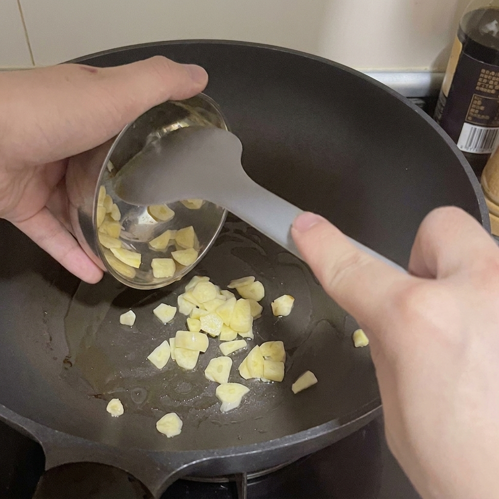 De lail finement tranché versé dun petit bol en métal dans une poêle chaude avec de lhuile.