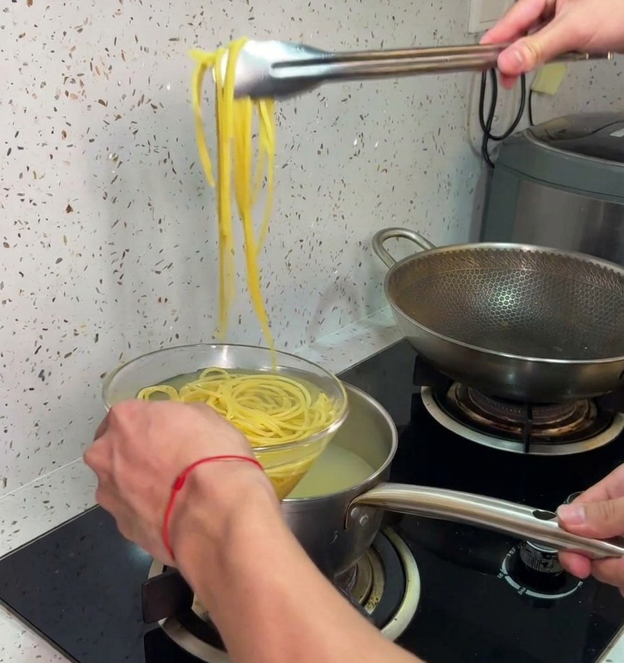 Une pince de cuisine soulevant des spaghettis cuits pour les plonger directement dans un bol deau froide.