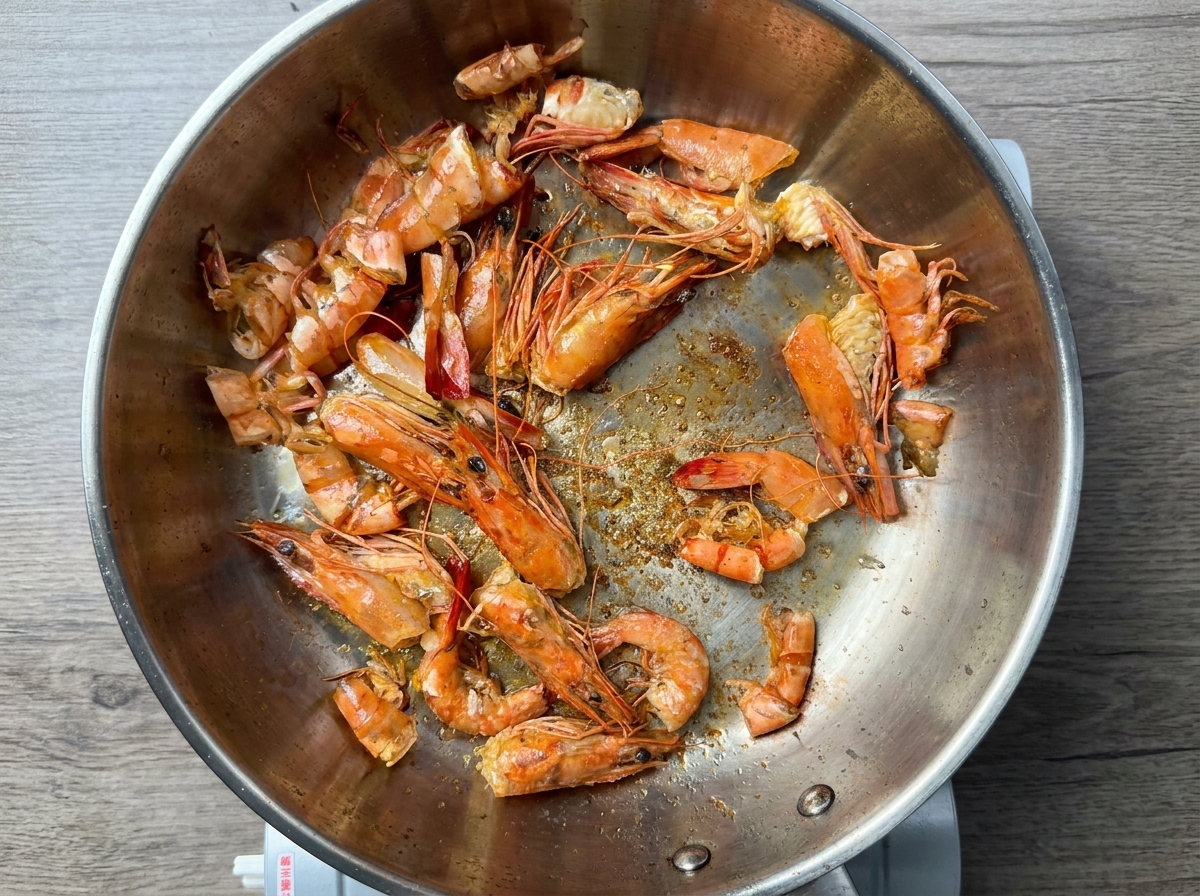 Carapaces de crevettes frisant dans lhuile chaude dune poêle en inox.