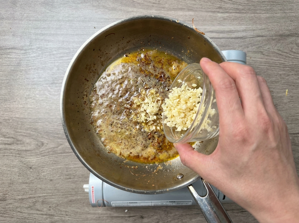 Ail émincé versé dans une poêle chaude avec du beurre fondu et de lhuile.
