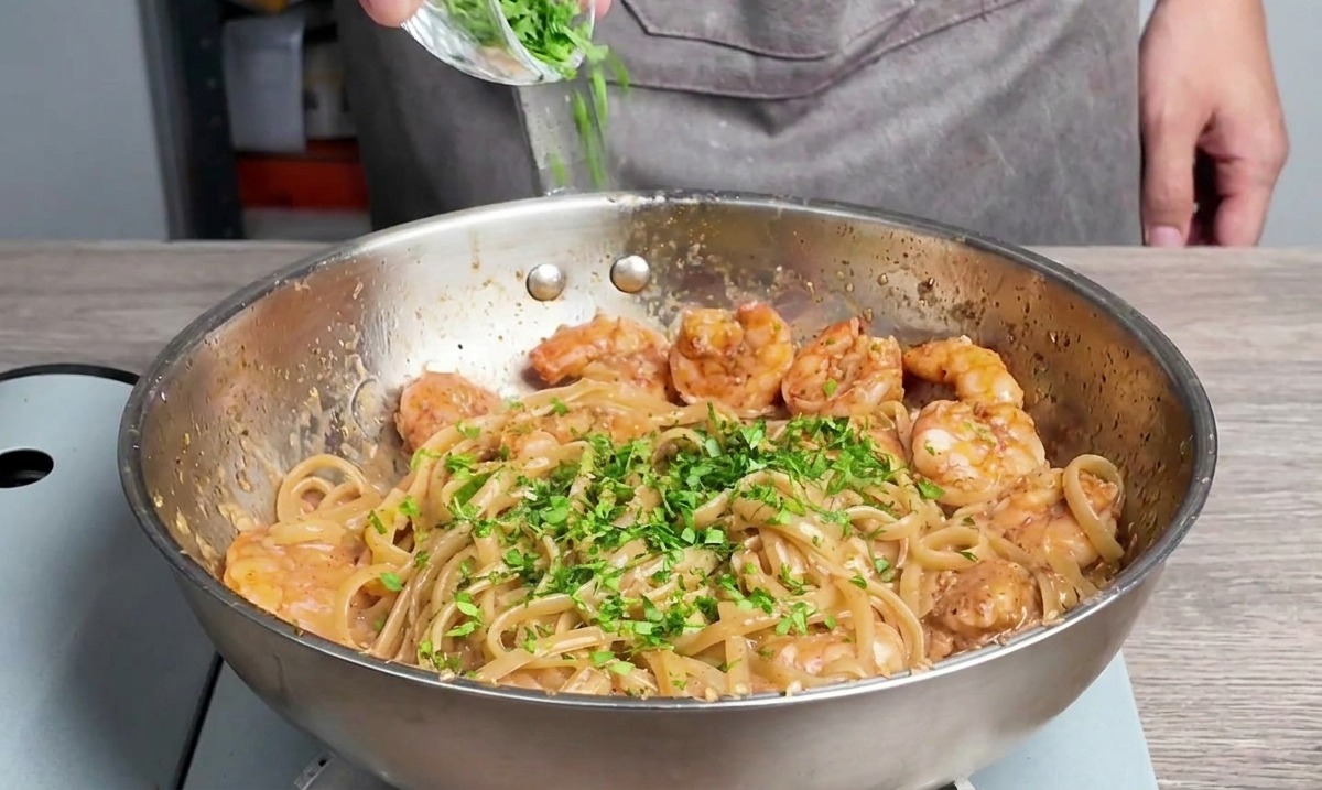 Persil frais haché saupoudré sur les linguines et les crevettes.