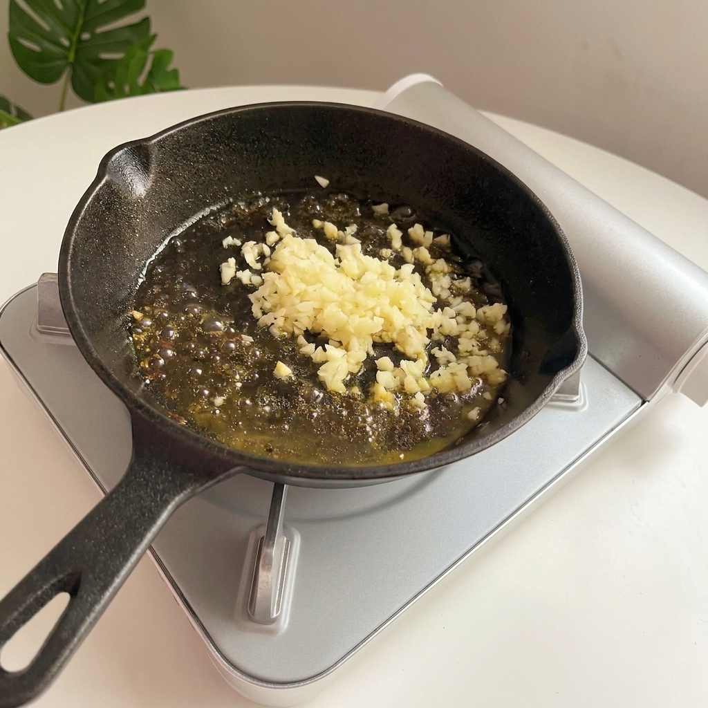 Ail haché frémissant et devenant doré dans le beurre fondu à lintérieur dune poêle en fonte.