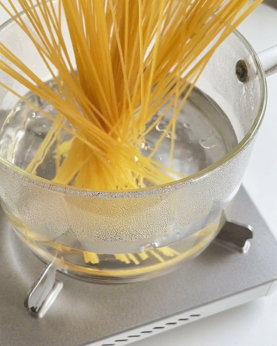 Un faisceau de spaghetti secs plongé dans une casserole deau bouillante.