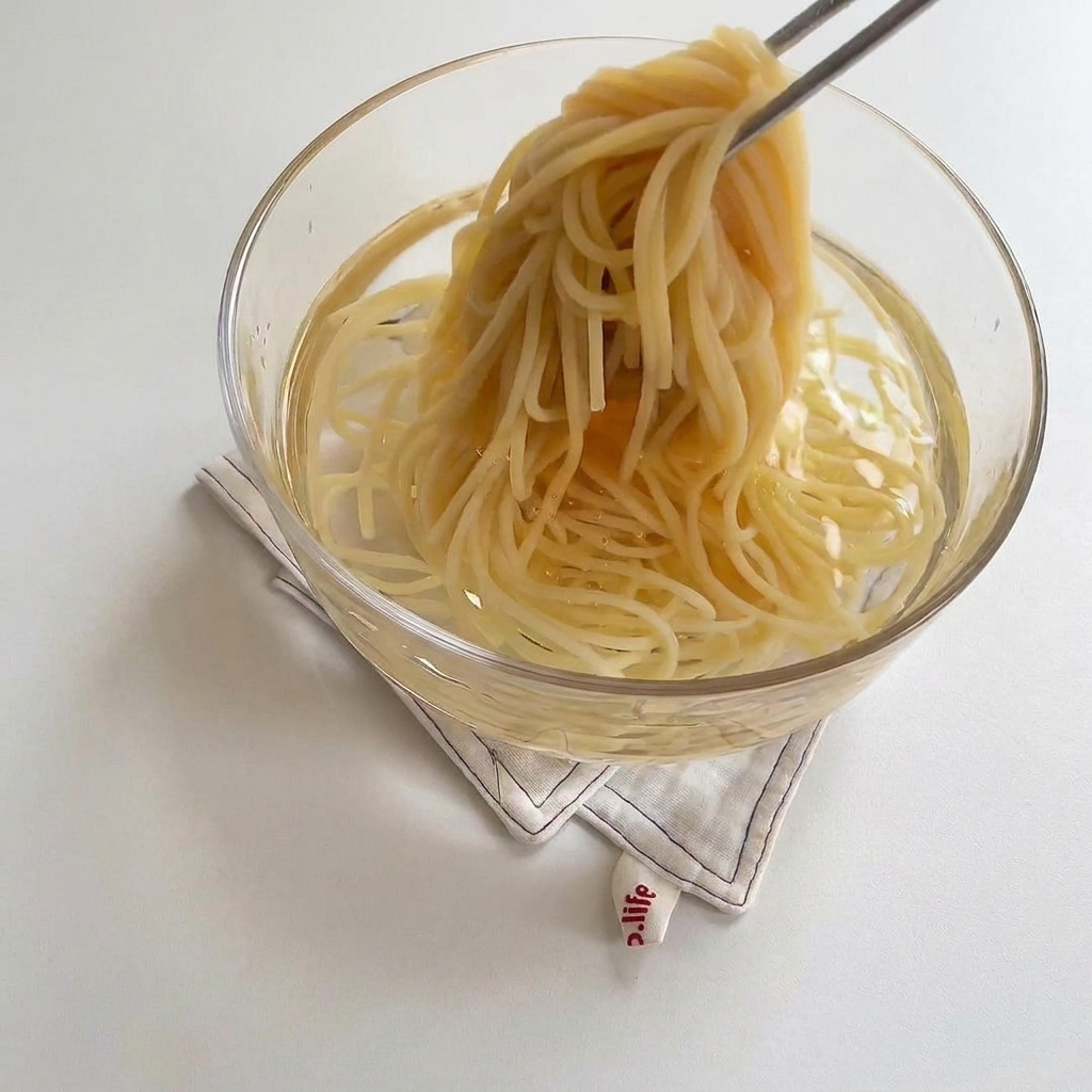 Des spaghetti cuits placés dans un bol deau froide pour stopper la cuisson.