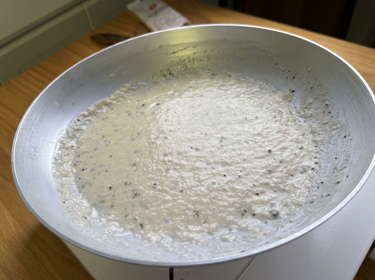 Gros plan dune pâte lisse et crémeuse faite de Pecorino et de poivre noir dans une poêle.