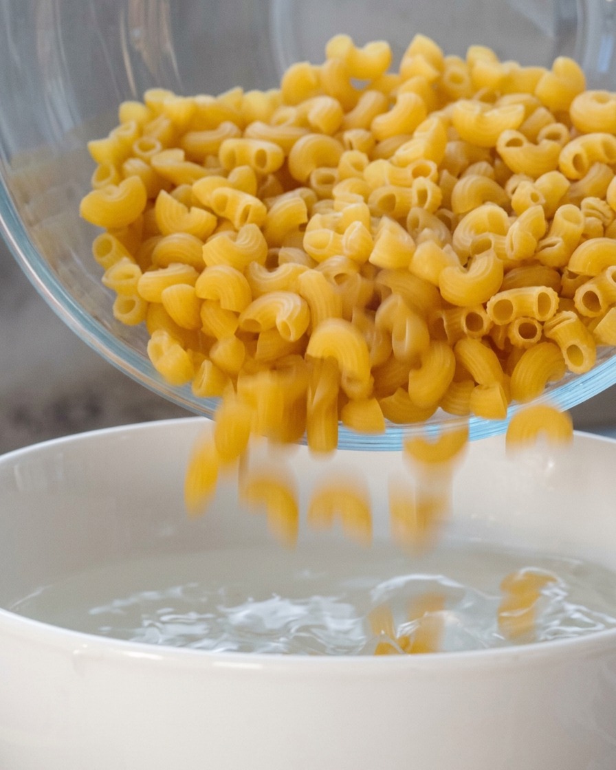Macaronis en spirale secs versés dun bol dans une casserole deau bouillante.