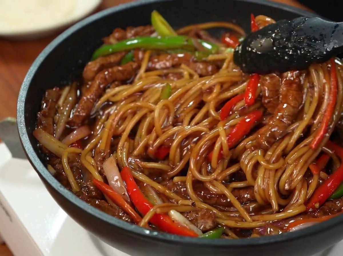 Assiette de spaghetti au bœuf et poivrons décorée de persil frais haché.