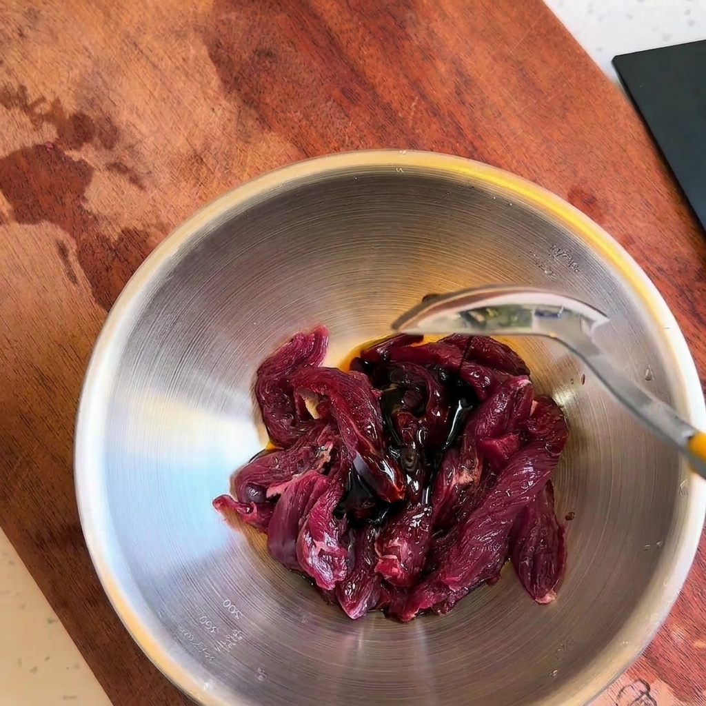 Ajout de sauces liquides foncées sur les lamelles de bœuf cru à laide dune cuillère.