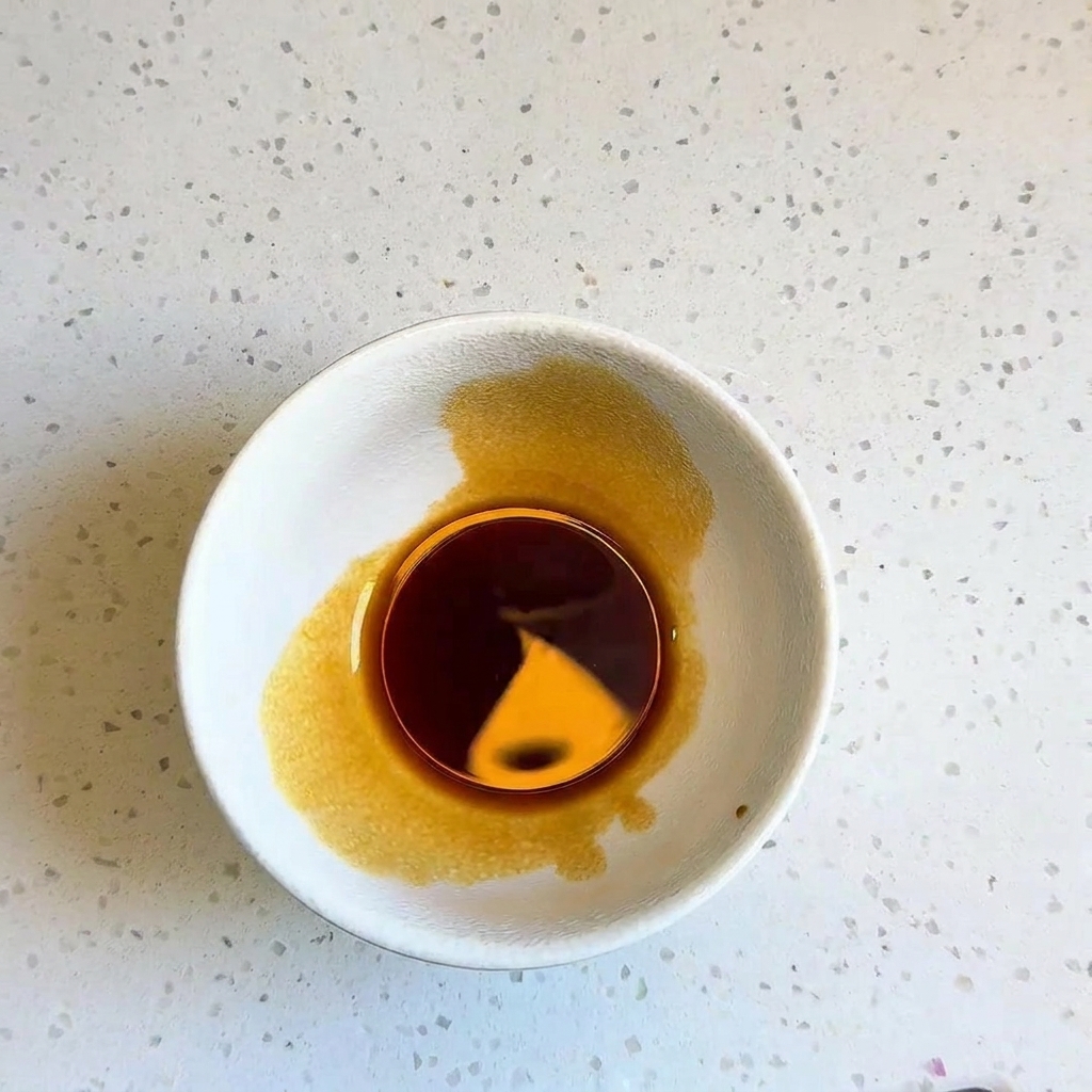 Petit bol blanc contenant une sauce sombre bien mélangée.