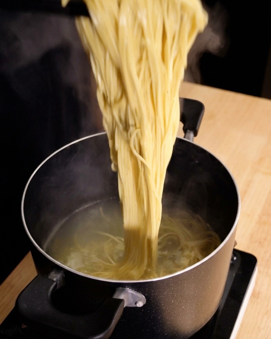 Un grand amas de spaghettis fumants étant soulevé directement dune casserole deau chaude avec une pince.