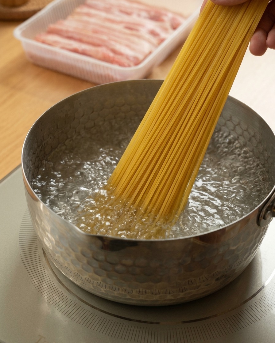 Une main plongeant des spaghetti dans leau bouillante.