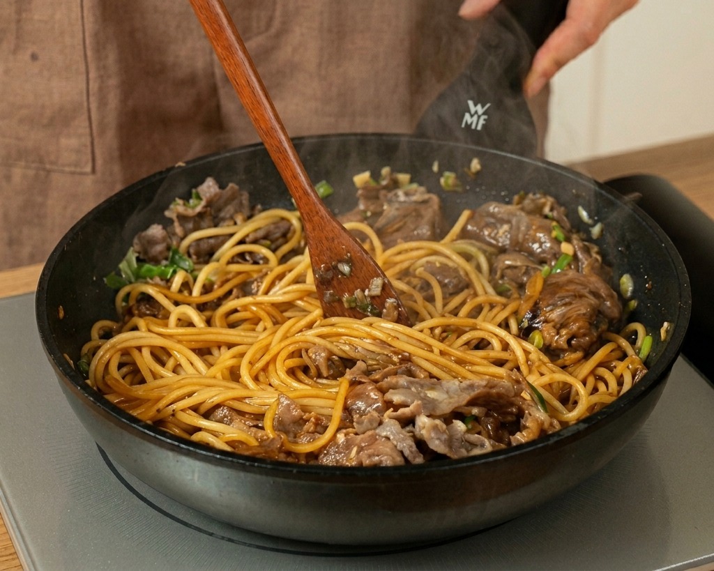 Mélange des pâtes, du bœuf et de la sauce avec une spatule en bois.