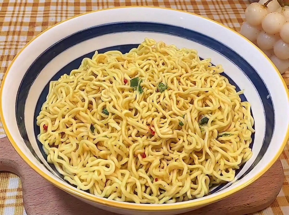 Nouilles ramen cuites et ondulées soigneusement disposées au centre dun bol en céramique bleu et blanc.