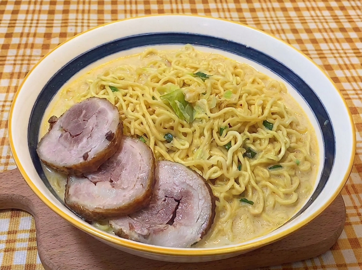 Trois tranches de porc chashu braisé déposées sur des nouilles ramen dans un bouillon crémeux.