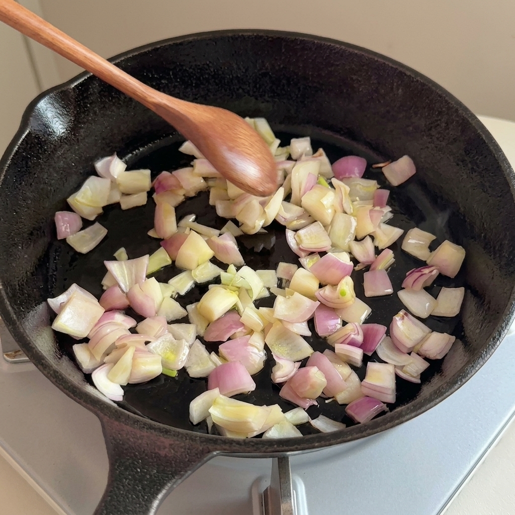 Oignons hachés sautant dans une poêle en fonte avec une cuillère en bois.