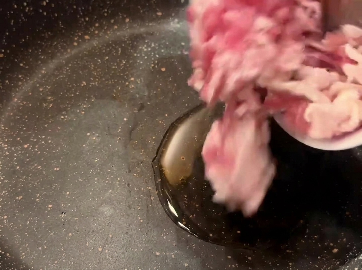 Morceaux de bacon cru versés dun bol dans une poêle sombre avec de lhuile de cuisson chaude.