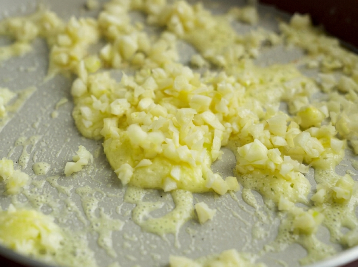 De fins morceaux dail haché cuisant doucement dans un mélange bouillonnant de beurre fondu et de fécule de maïs.