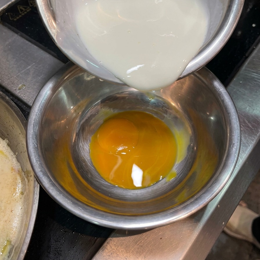 Crème liquide versée dans un petit bol contenant un jaune dœuf bien orangé.