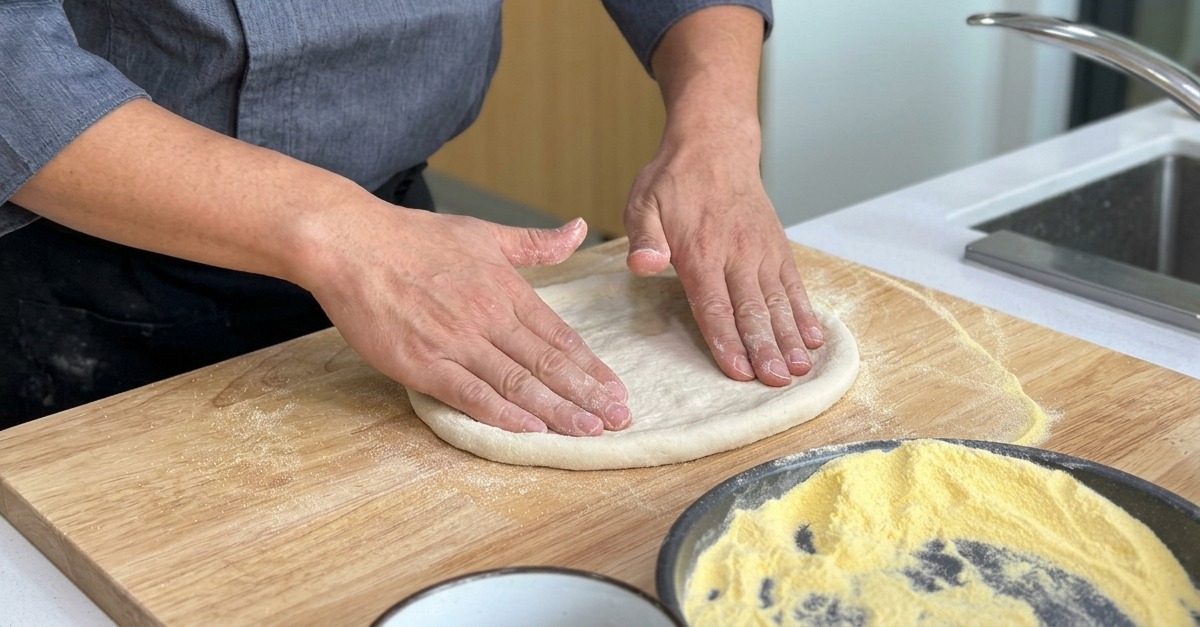 Étirement de la base de la pizza sur une planche en bois, gardant un bord plus épais.