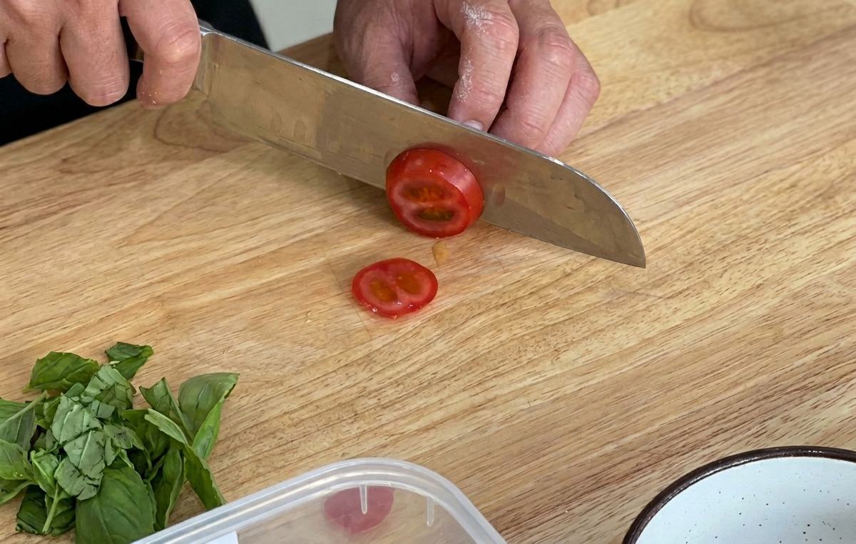 Découpe de tomates cerises fraîches sur une planche en bois.