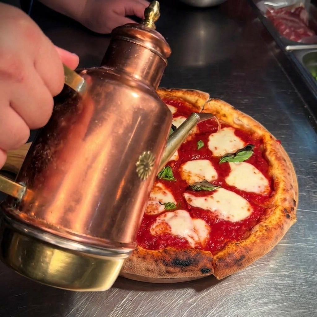 Huile dolive dorée versée dun huilier en cuivre sur une pizza Margherita fraîchement coupée.