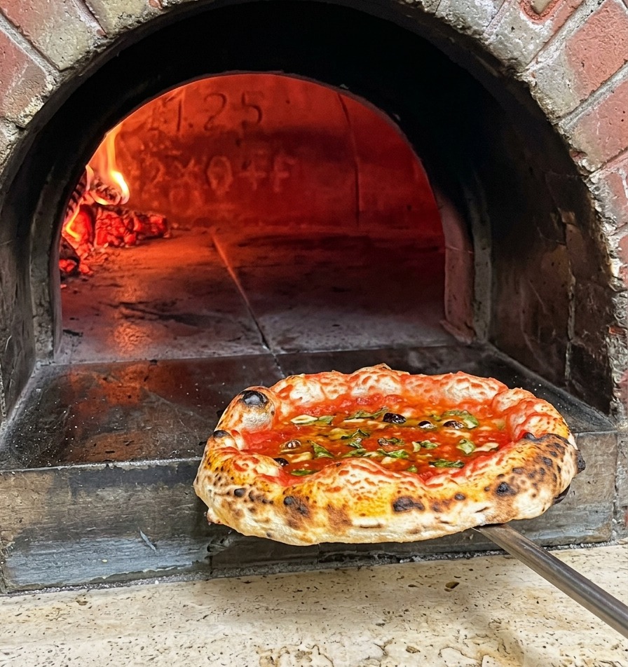 Une pizza napolitaine fraîchement cuite avec une croûte tachetée retirée dun four à bois sur une pelle en métal.