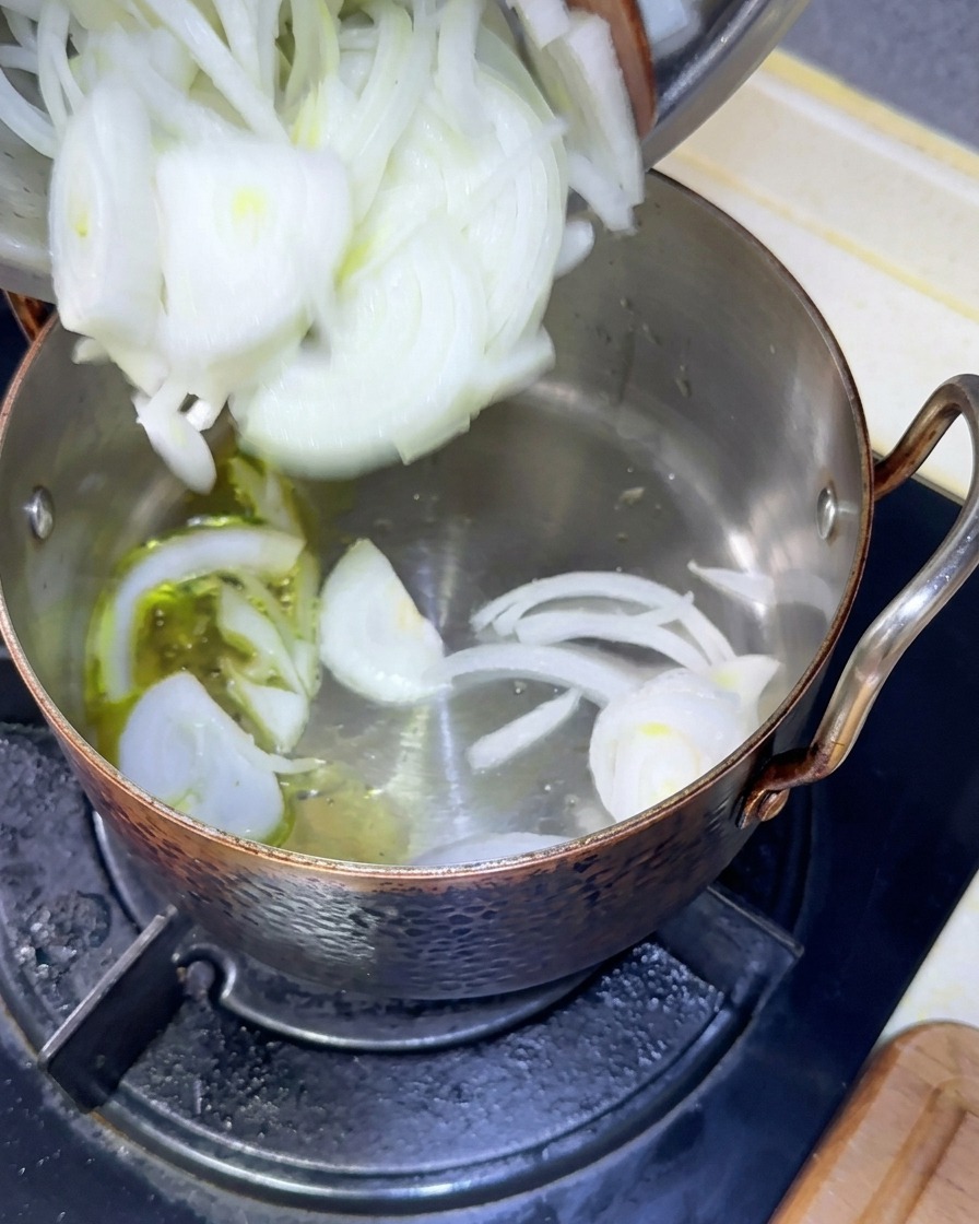 Lamelles doignons blancs versées dun bol vers une sauteuse contenant de lhuile chaude.