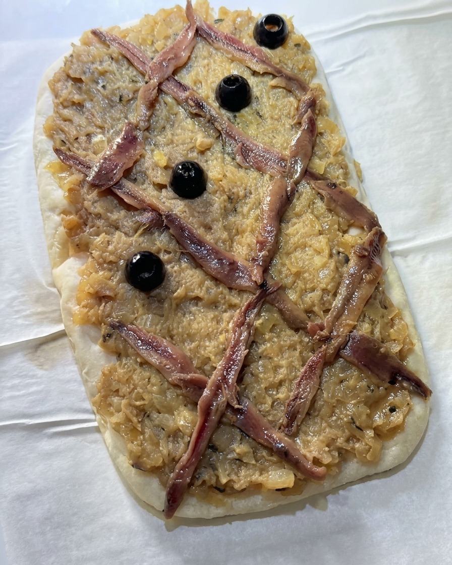 Olives noires entières placées au centre des losanges formés par les anchois.