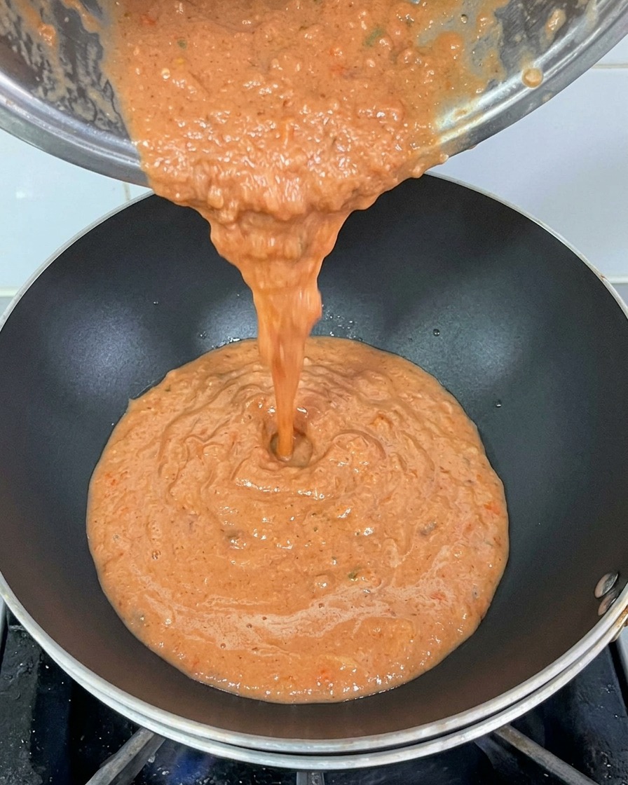 Versement de la sauce tomate mixée dans un wok chaud avec un peu dhuile.