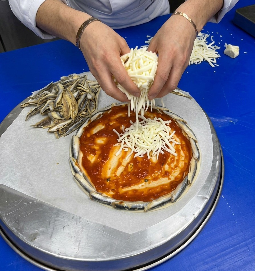 Mains parsemant généreusement du fromage râpé sur la sauce tomate.