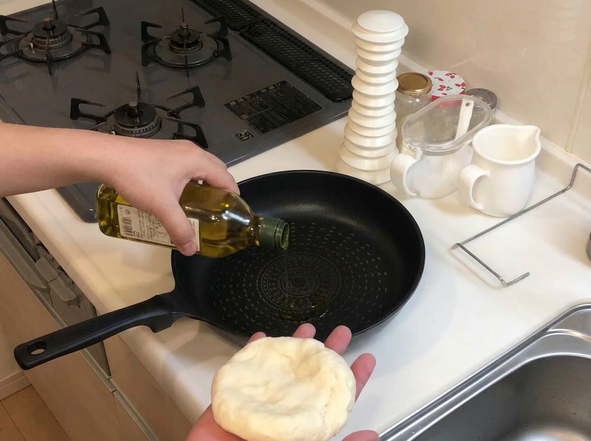Verser de lhuile dolive dune bouteille verte dans une poêle antiadhésive noire froide, tout en tenant une portion de pâte dans lautre main.