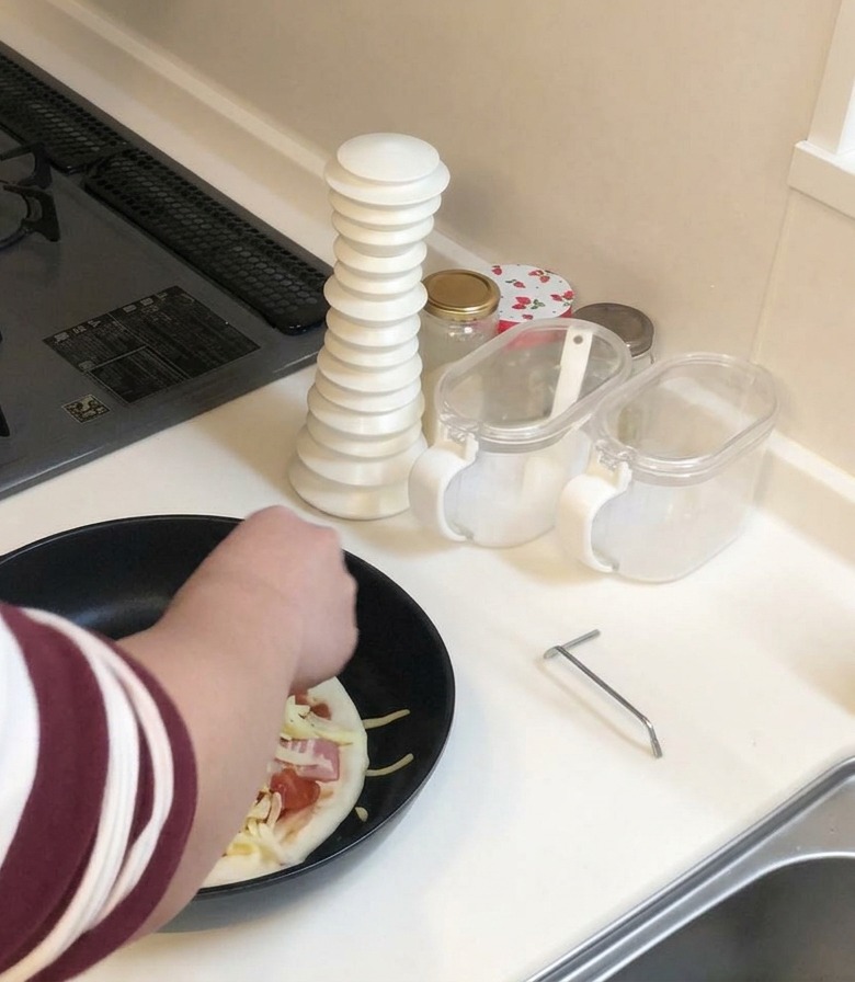 Une personne ajoutant une généreuse poignée de fromage râpé sur la pizza dans la poêle.