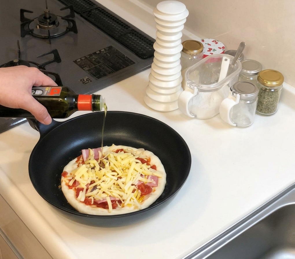 Une main tenant une bouteille dhuile dolive et en versant un filet sur la pizza non cuite et garnie de fromage dans une poêle noire.