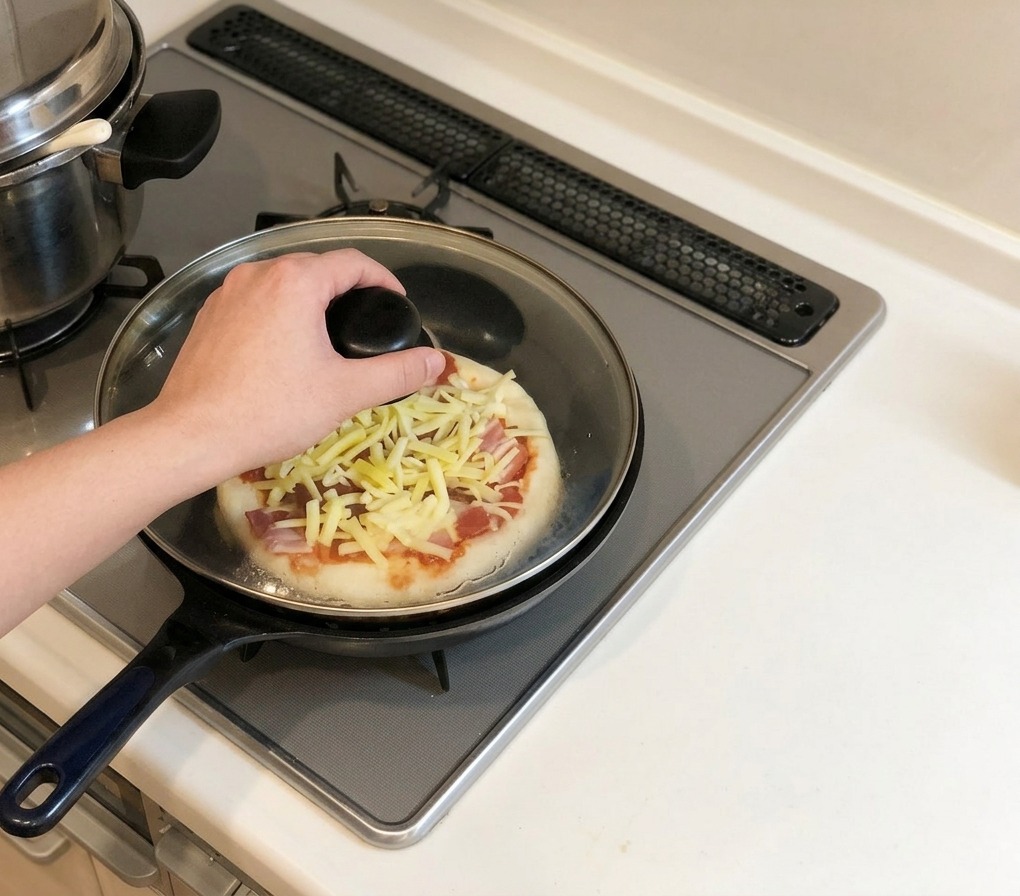 Une main posant un couvercle en verre sur une poêle contenant la pizza sur une cuisinière à gaz.