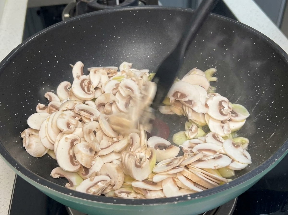 Tranches de champignons et gousses dail sautant dans une poêle chaude avec une spatule.