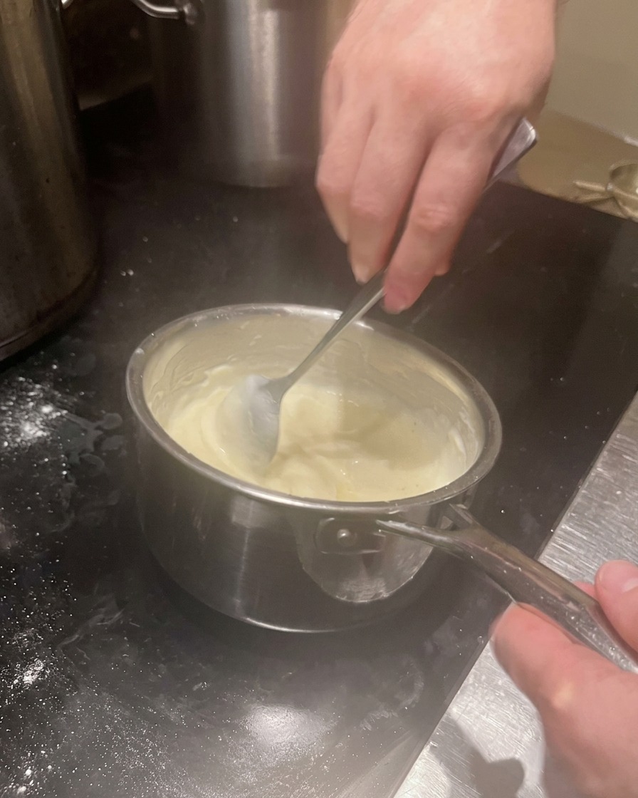 Sauce blanche crémeuse et épaisse remuée dans une casserole.