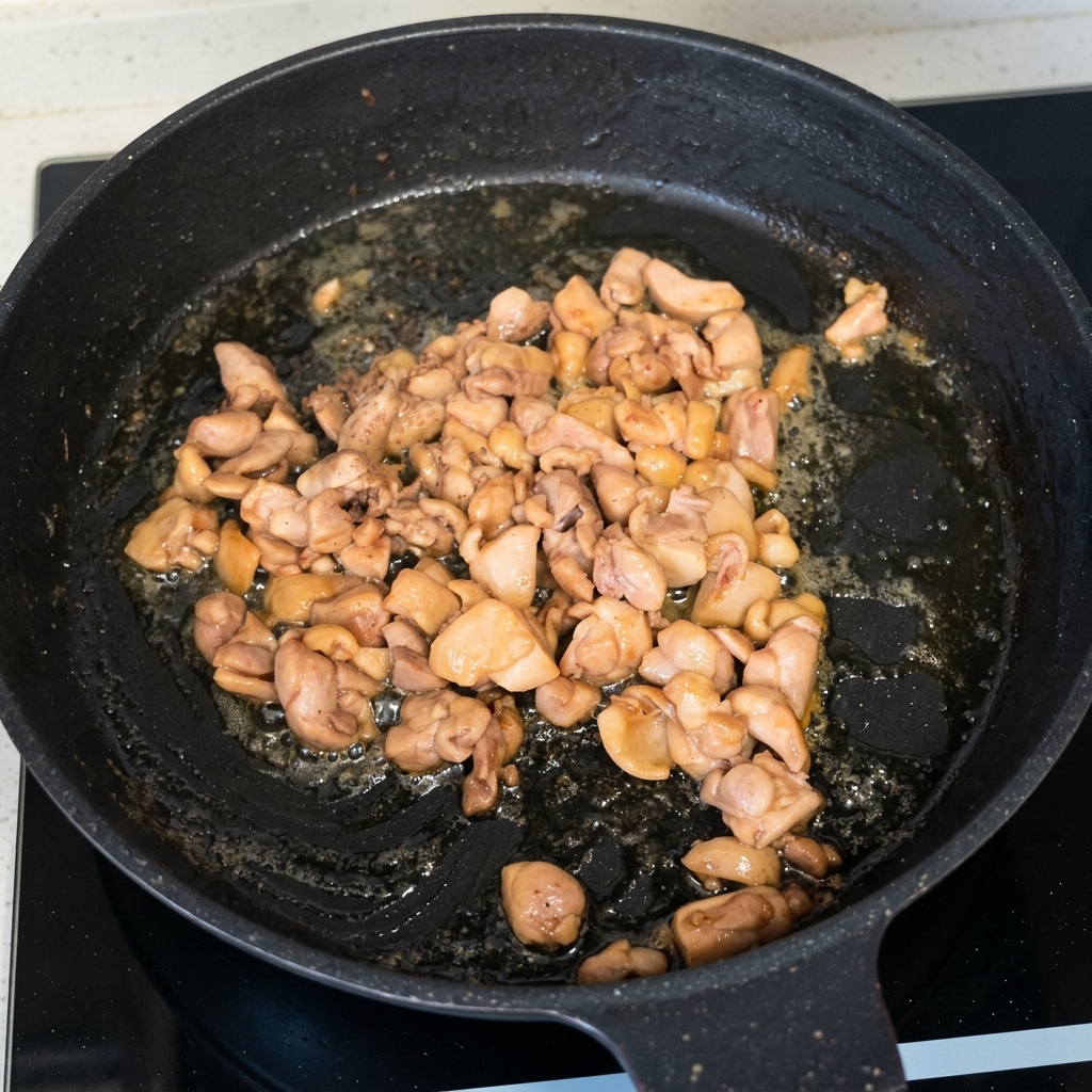 Morceaux de poulet cuits et dorés sautés dans une poêle noire.