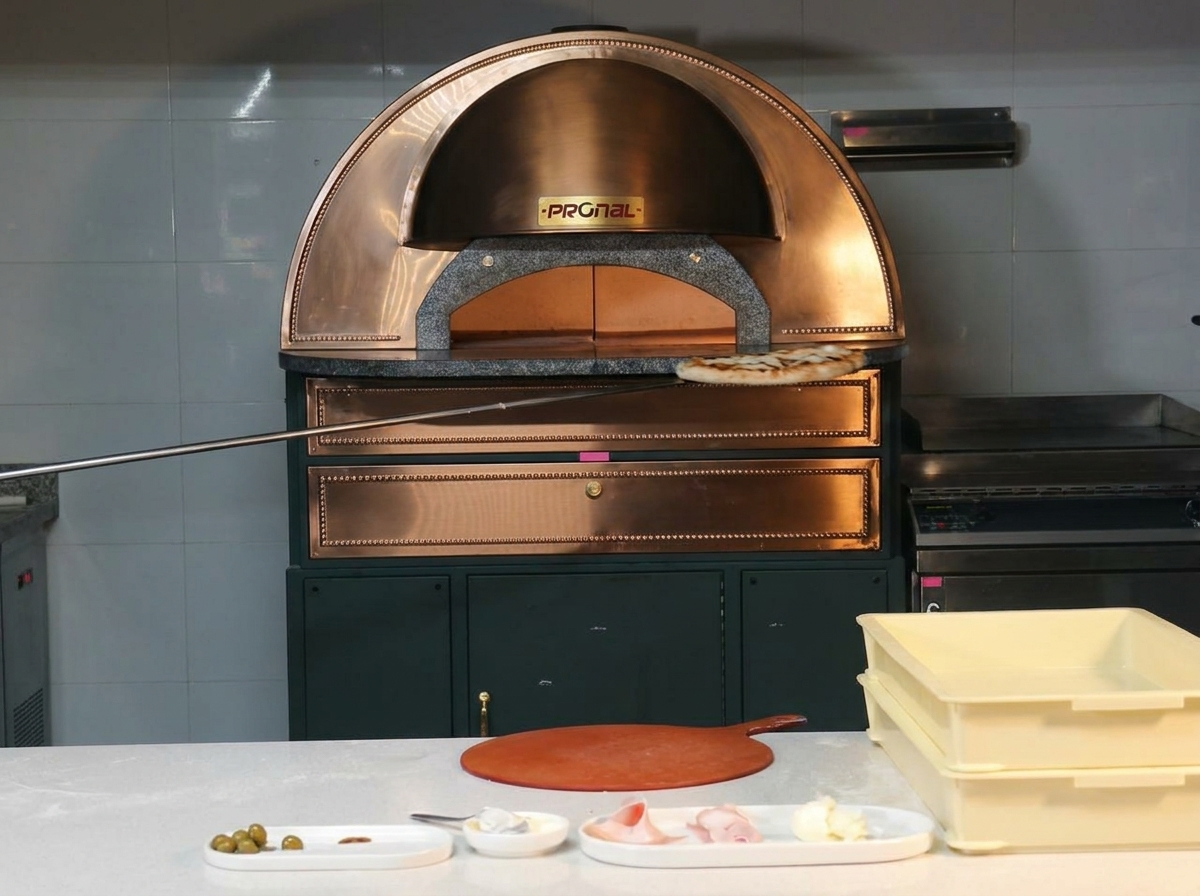 Une pizza parfaitement cuite avec une croûte alvéolée sortant dun four en cuivre sur une pelle en métal.