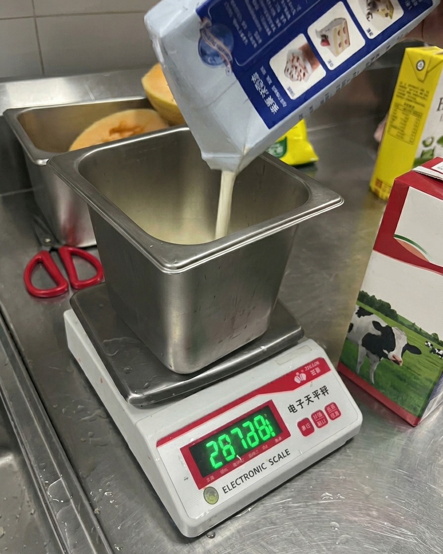 Du lait versé dune brique dans un récipient métallique rectangulaire posé sur une balance électronique.