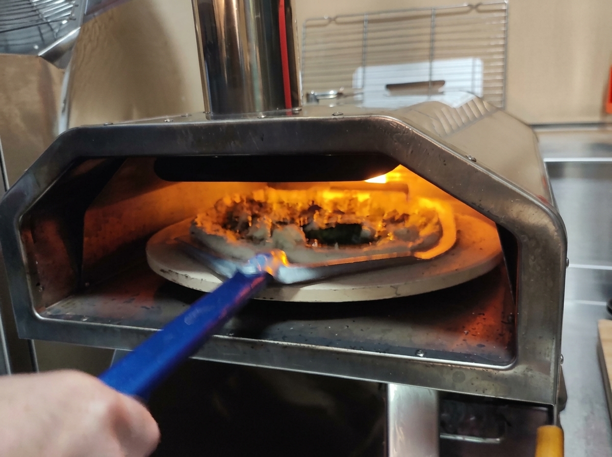 Utilisation dune pelle à pizza en métal perforée pour glisser la pizza crue dans un four chaud.