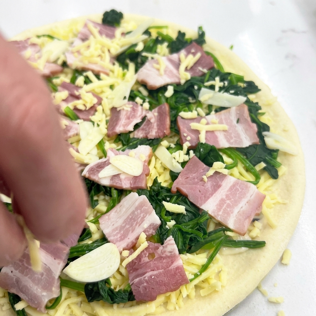 Une main saupoudrant une dernière couche légère de mozzarella sur la pizza garnie avant cuisson.